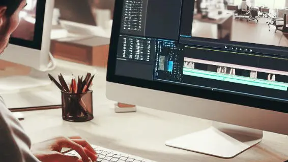 Ein VideoBearbeiter benutzt einen iMac, um einen Videoschnitt *sorglos* zu machen.